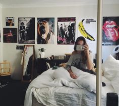 a woman taking a selfie in her bedroom with pictures on the wall behind her