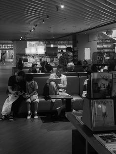 black and white photograph of people sitting on couches in a library with bookshelves