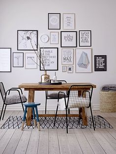 a dining room table with chairs and pictures on the wall above it, along with other furniture