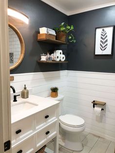 a white toilet sitting next to a bathroom sink under a mirror and shelf above it