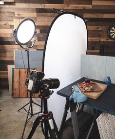 a photo studio setup up with a camera, light and tripod in front of a wooden wall