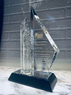 an award is displayed on a marble countertop with a brick wall in the background