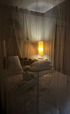 a bed with white sheets and a yellow lamp