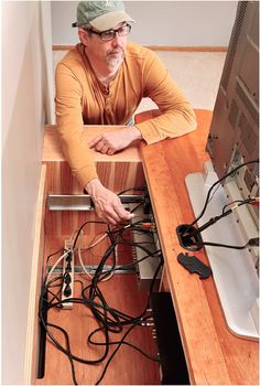 a man sitting at a desk with many wires in front of him and his computer