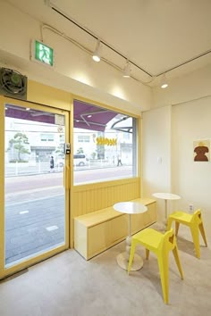 two yellow chairs sitting in front of a window next to a white table and bench