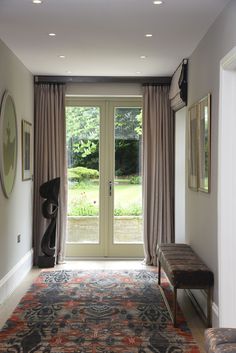 a room with a large rug and two benches in front of the door that leads to an outside patio