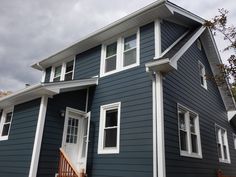 a blue house with white trim on the front and side windows, stairs leading up to the second floor