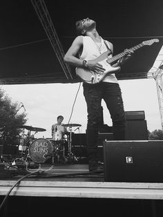 a man standing on top of a stage holding a guitar