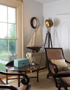 a living room filled with furniture and a sailboat on the window sill next to it