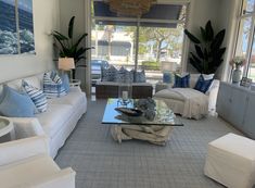 a living room filled with white couches and blue pillows on top of each other