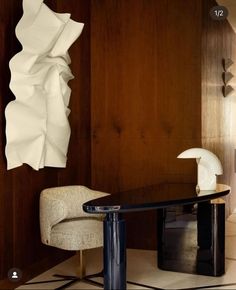 a chair and table in a room with wood paneling on the wall behind it