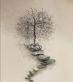 a tree that is sitting on some rocks and has stones in the shape of a spiral staircase