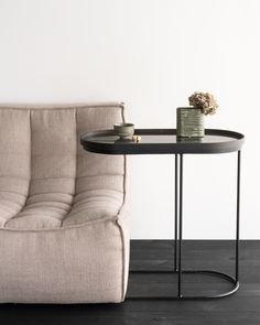 a couch and table in front of a white wall with a vase on it's side