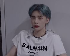 a man with blue hair and piercings wearing a white t - shirt that says batman paris