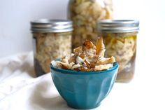 a bowl filled with food sitting on top of a table next to two mason jars