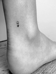 a black and white photo of a person's foot with a tiny heart tattoo on it