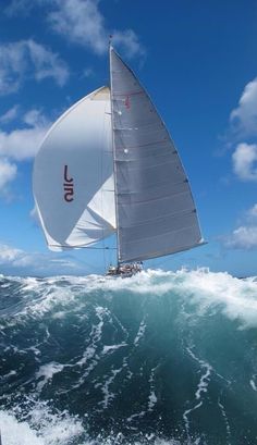 a sailboat is sailing through the ocean on a sunny day with blue skies and white clouds