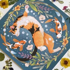 a card with an orange and white cat laying on it's back surrounded by flowers