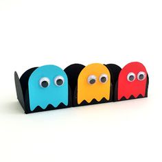 three paper monsters are lined up in a row on a white surface with eyes and noses