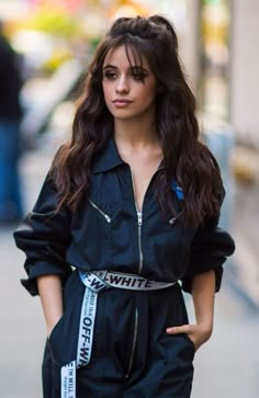 a woman with long dark hair wearing a black jumpsuit