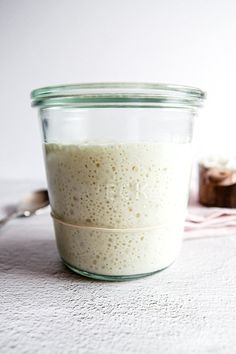 a glass jar filled with food sitting on top of a table next to a spoon