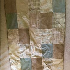 a brown and green patchwork quilt laying on top of a bed