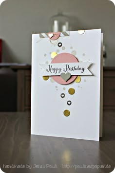 a happy birthday card with confetti and polka dots on white paper, sitting on a table