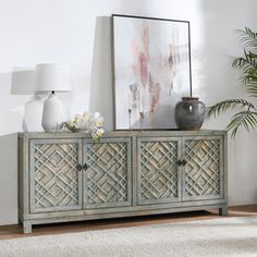 a living room scene with focus on the sideboard and plant in the foreground