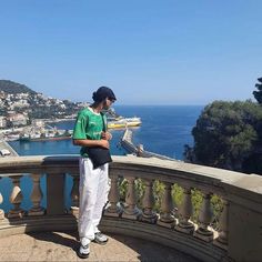 a man standing on top of a balcony next to the ocean and looking at his cell phone