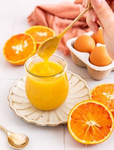 someone is spooning orange juice into a jar with an egg in the back ground