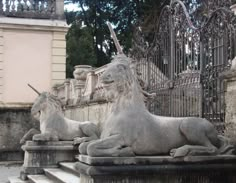 two statues of lions sitting on top of stone steps in front of a gated area