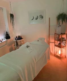 a white bed in a room next to a window with plants on the windowsill