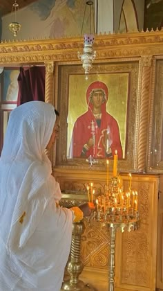 a woman standing in front of a painting with candles