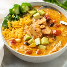 a white bowl filled with chicken, rice and veggie soup on top of a table