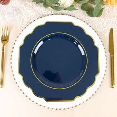 a blue plate with gold trim sits on a lace tablecloth next to silverware