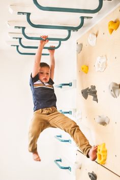 a young boy climbing up the side of a wall with his hands in the air