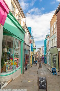 people walking down the sidewalk in front of shops on a sunny day with blue skies