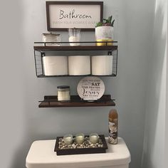 a white toilet sitting in a bathroom next to a shelf filled with jars and candles