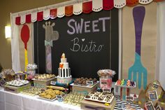 a table topped with lots of desserts next to a chalkboard that says sweet bistro