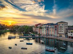 boats are floating on the water in front of some buildings and trees at sunset or dawn