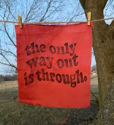 the only way out is through sign hanging on a clothes line next to a tree