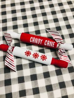 two red and white candy canes sitting on top of a checkered table cloth