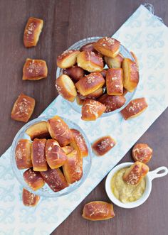 two bowls filled with pretzels on top of a table next to some dipping sauce