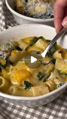 two bowls of pasta and spinach soup on a checkered tablecloth with a spoon