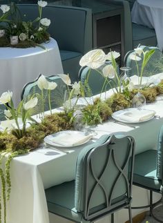 the table is set with white flowers and greenery for an elegant dinner or party