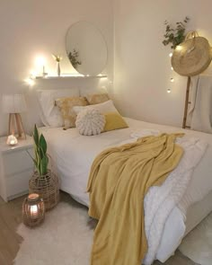 a white bed topped with pillows and blankets next to a night stand filled with candles