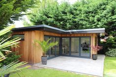 a small wooden building sitting in the middle of a lush green yard