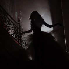 a woman is walking down the stairs in a dark room with her arms spread out