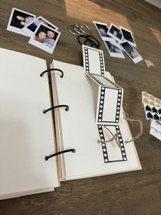 an open book on a table with photos and clips attached to the pages that have been cut out