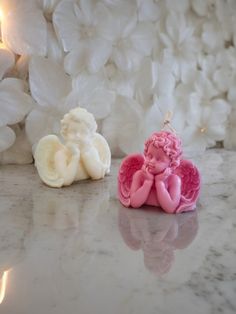 an angel figurine sitting on a marble counter next to some white and pink flowers